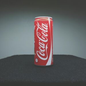 A classic Coca-Cola can showcased on a dark surface with minimal lighting.